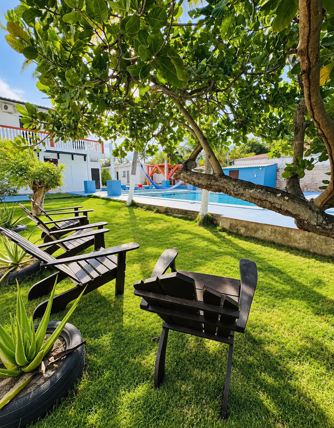 Jardín tropical con sillas a la sombra, hamaca y piscina del rancho