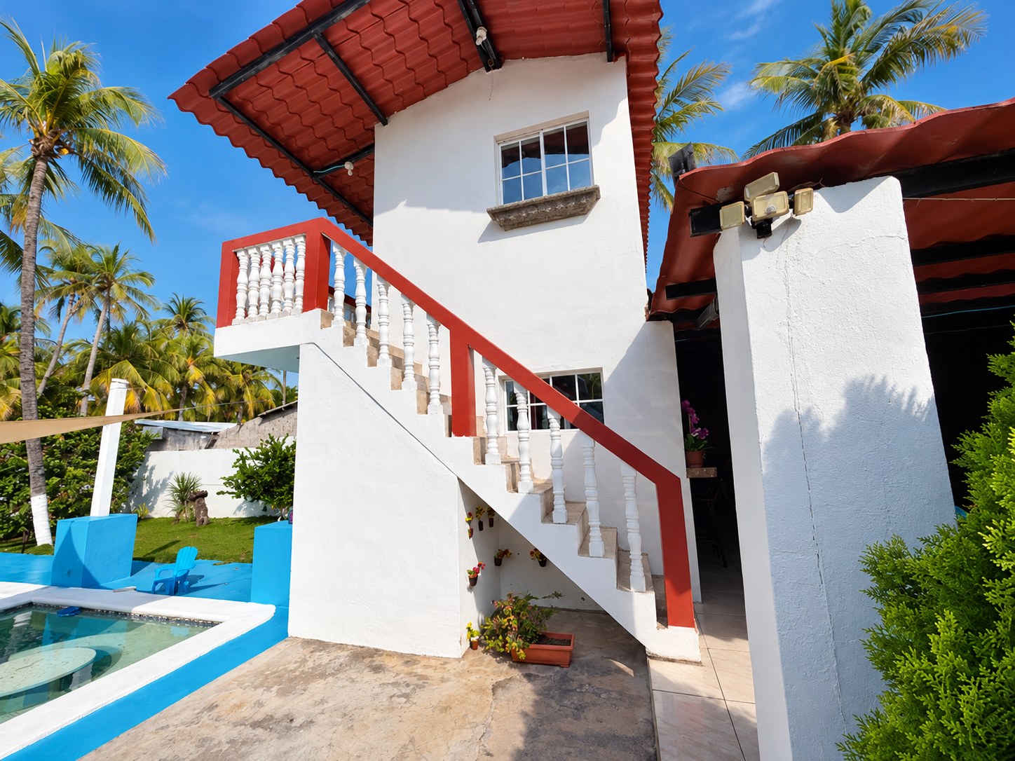 Casa blanca con escalera exterior, palmeras y piscina